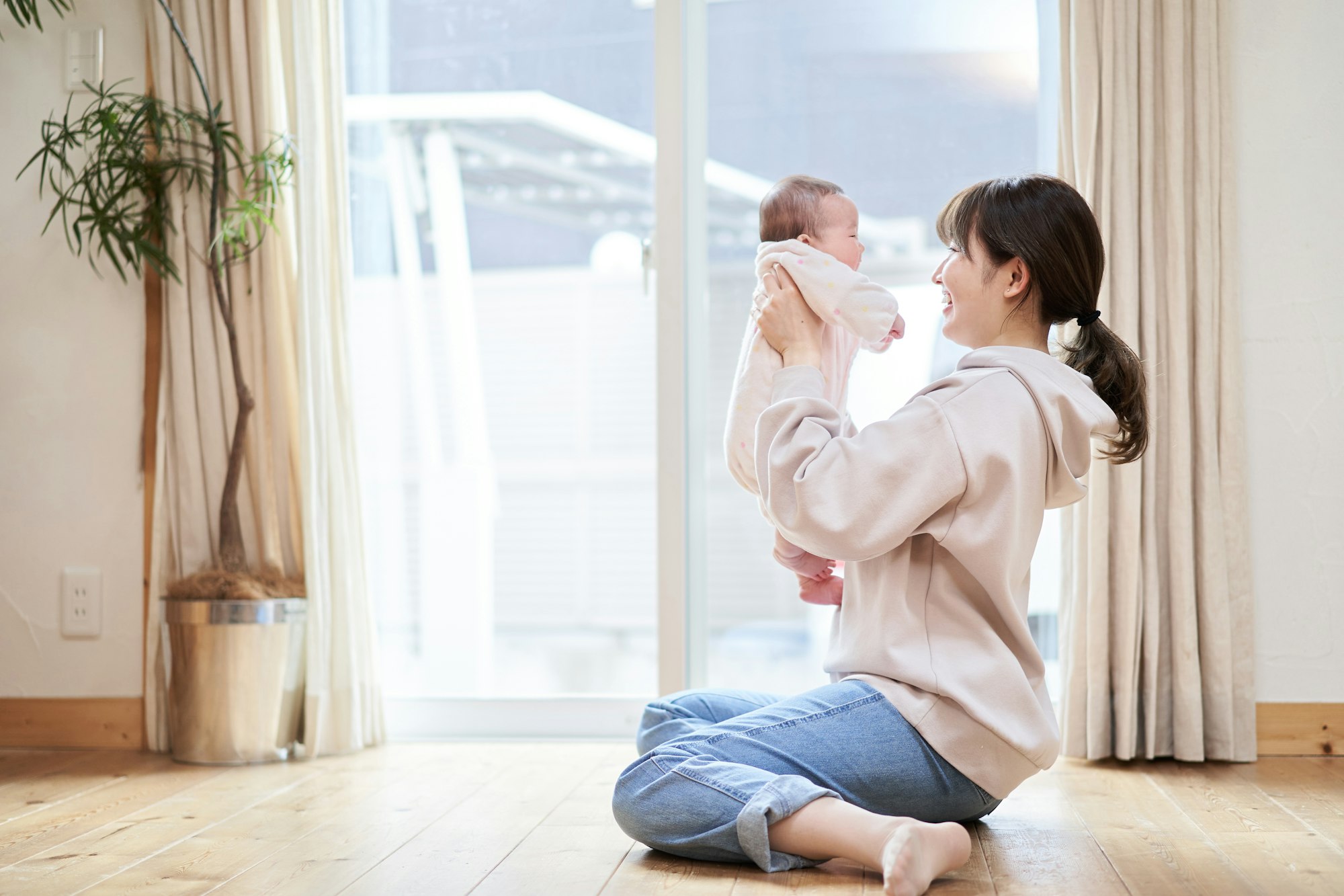 Asian mom holding a baby in the living room