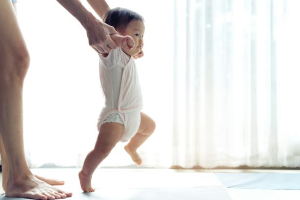 Happy little baby learning to walk with mother help at home. Baby growth and development