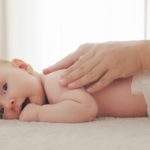 Mother doing massage on her healthy infant baby.