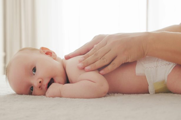 Mother doing massage on her healthy infant baby.