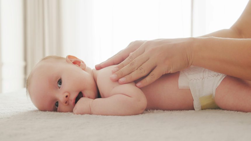 Mother doing massage on her healthy infant baby.