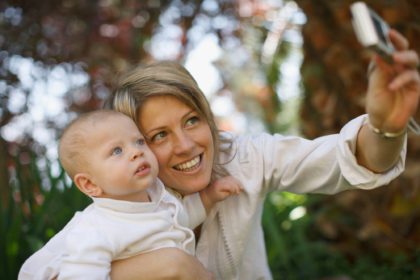 Mother taking picture with baby outdoors