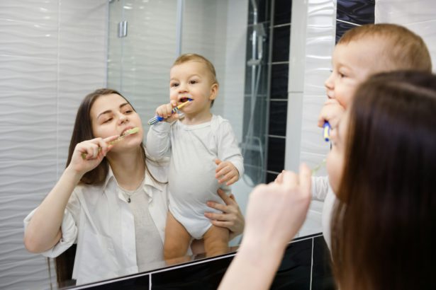 Mother with baby brushing teeth in bathroom