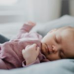 Portrait of cute newborn baby girl, sleeping an lying on sofa indoors at home.