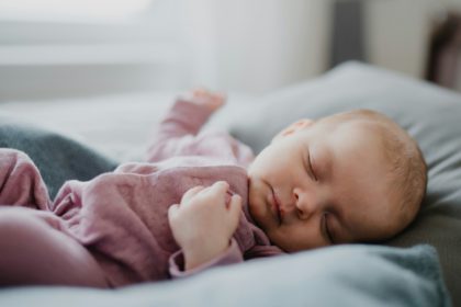 Portrait of cute newborn baby girl, sleeping an lying on sofa indoors at home.