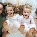Top view, happy and family with twins in bed smiling together with parents in the morning at home o