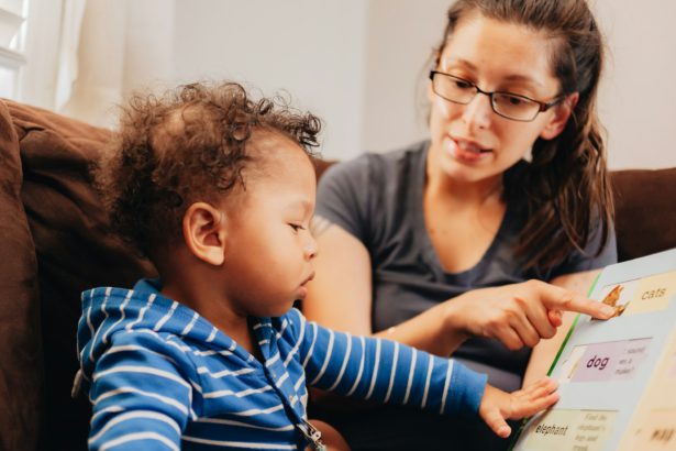 Young millennial mother at home teaching mixed race baby boy his first words, milestone development